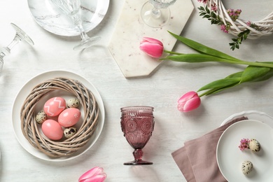 Festive Easter table setting with painted eggs on wooden background, top view