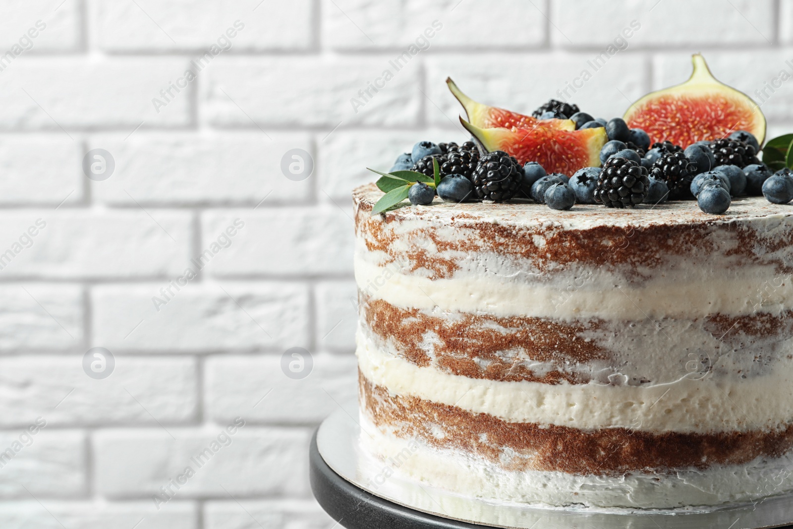 Photo of Delicious homemade cake with fresh berries near brick wall, closeup