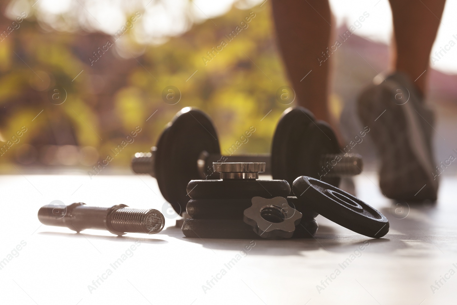 Photo of Adjustable dumbbells and male athlete on background. Space for text