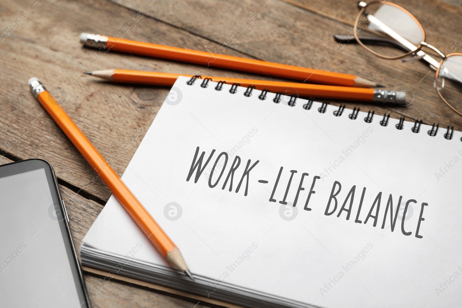 Image of Work-life balance concept. Notebook, smartphone and pencils on wooden table, closeup