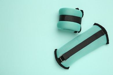 Photo of Stylish weighting agents on turquoise background, flat lay. Space for text