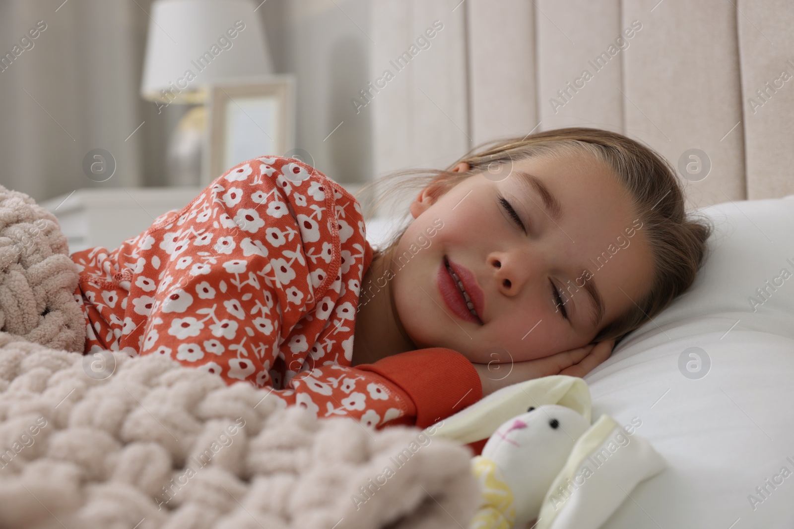 Photo of Cute little girl with toy bunny sleeping in bed at home