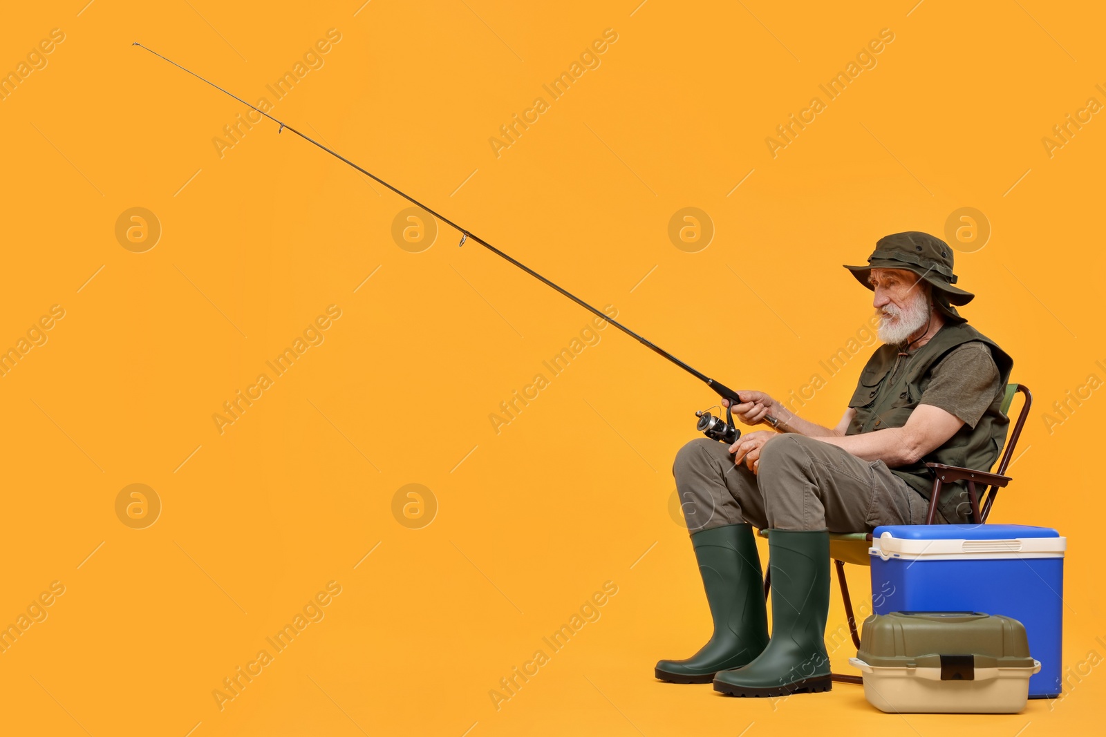 Photo of Fisherman with fishing rod on chair against yellow background, space for text