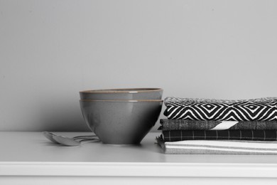 Photo of Kitchen towels and tableware on white countertop near wall