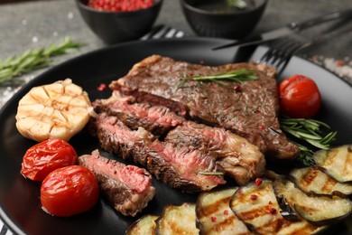 Photo of Delicious grilled beef steak with vegetables and spices on plate, closeup