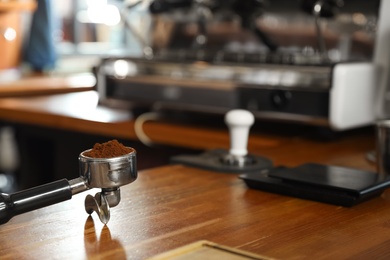 Portafilter with milled coffee on counter in bar. Space for text