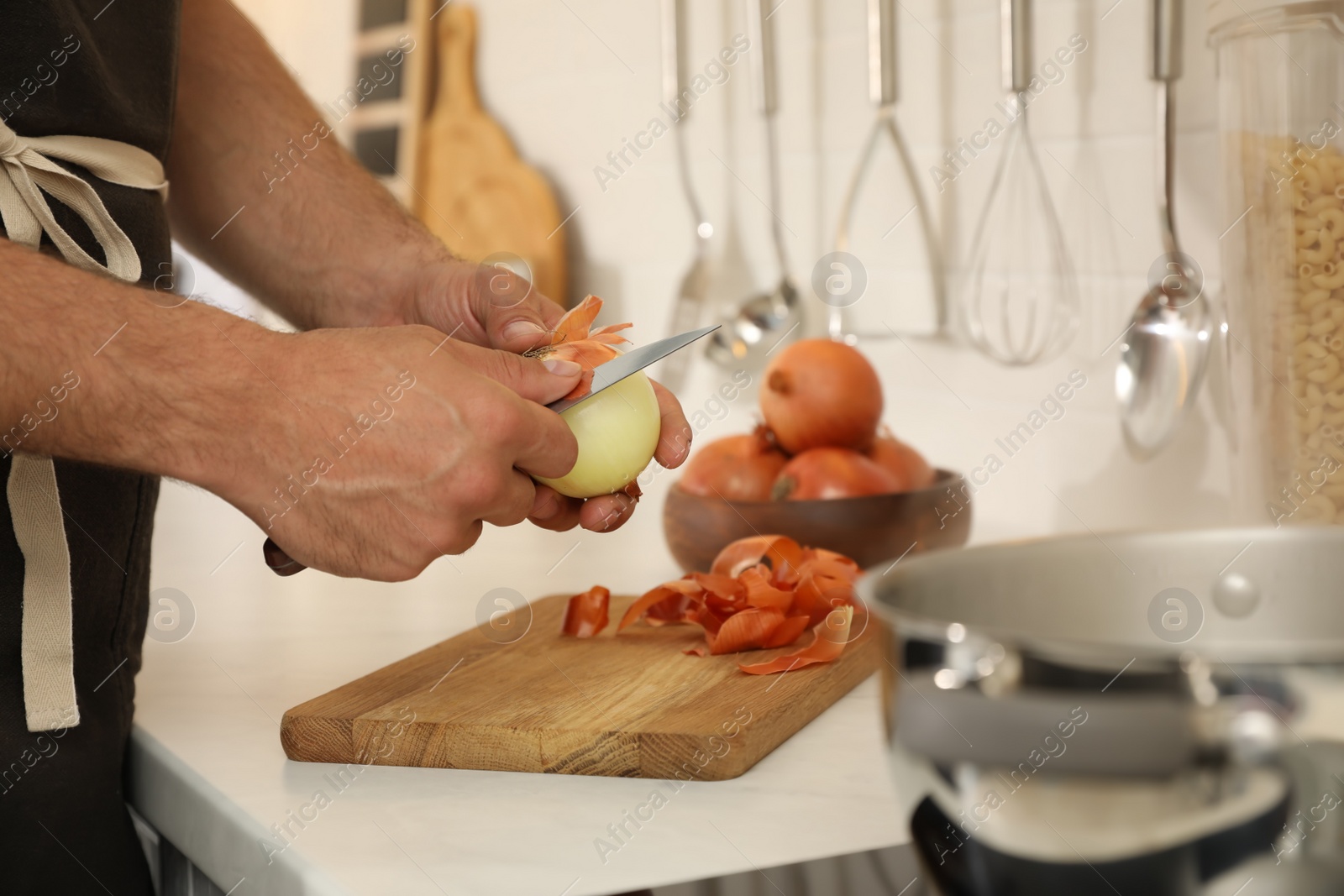 Photo of Man peeling onion at kitchen counter, closeup. Preparing vegetable