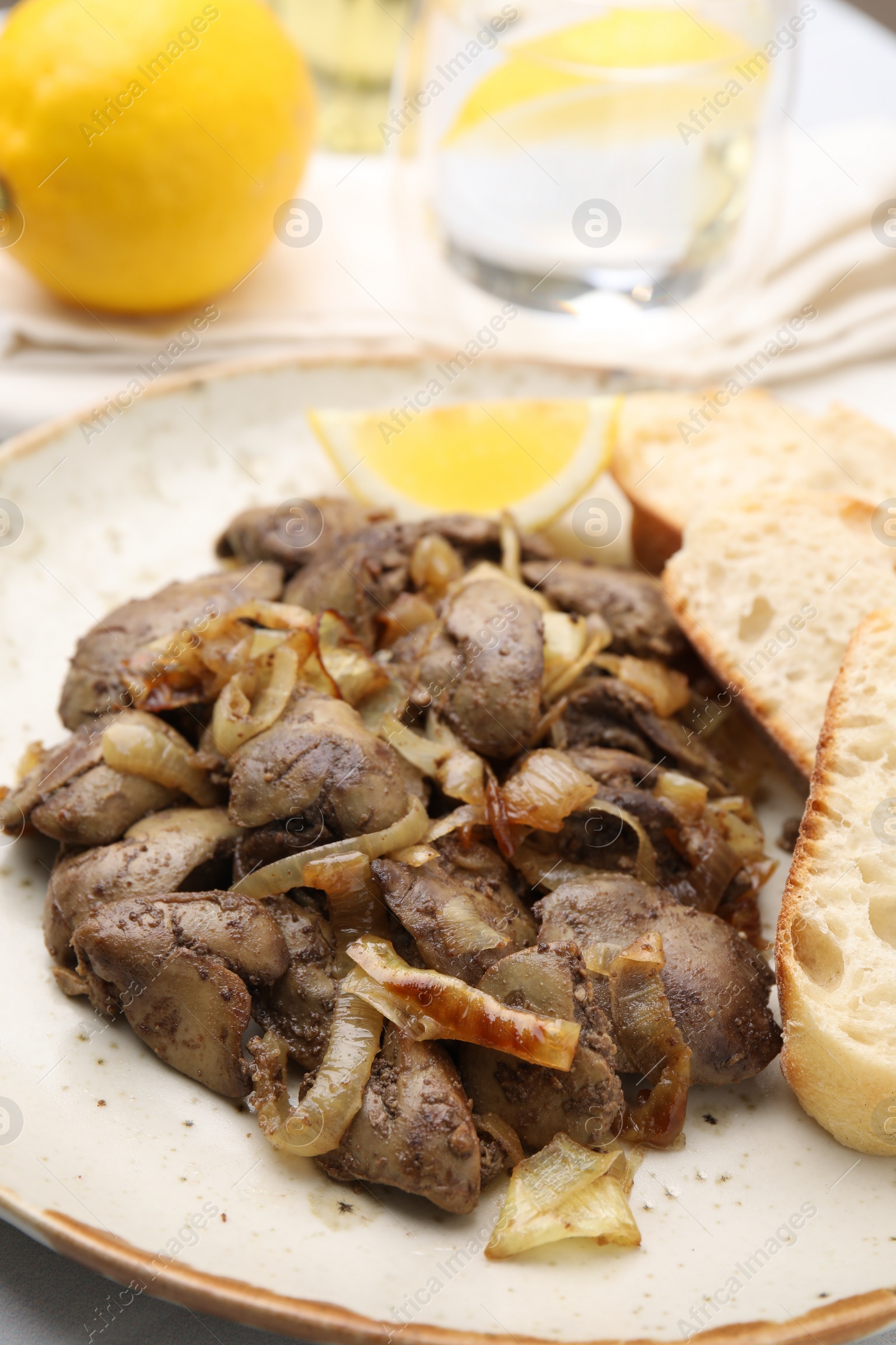 Photo of Tasty fried chicken liver with onion served on white table, closeup