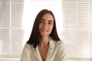 Photo of Young woman talking to her coworkers through video conference indoors, view from webcam