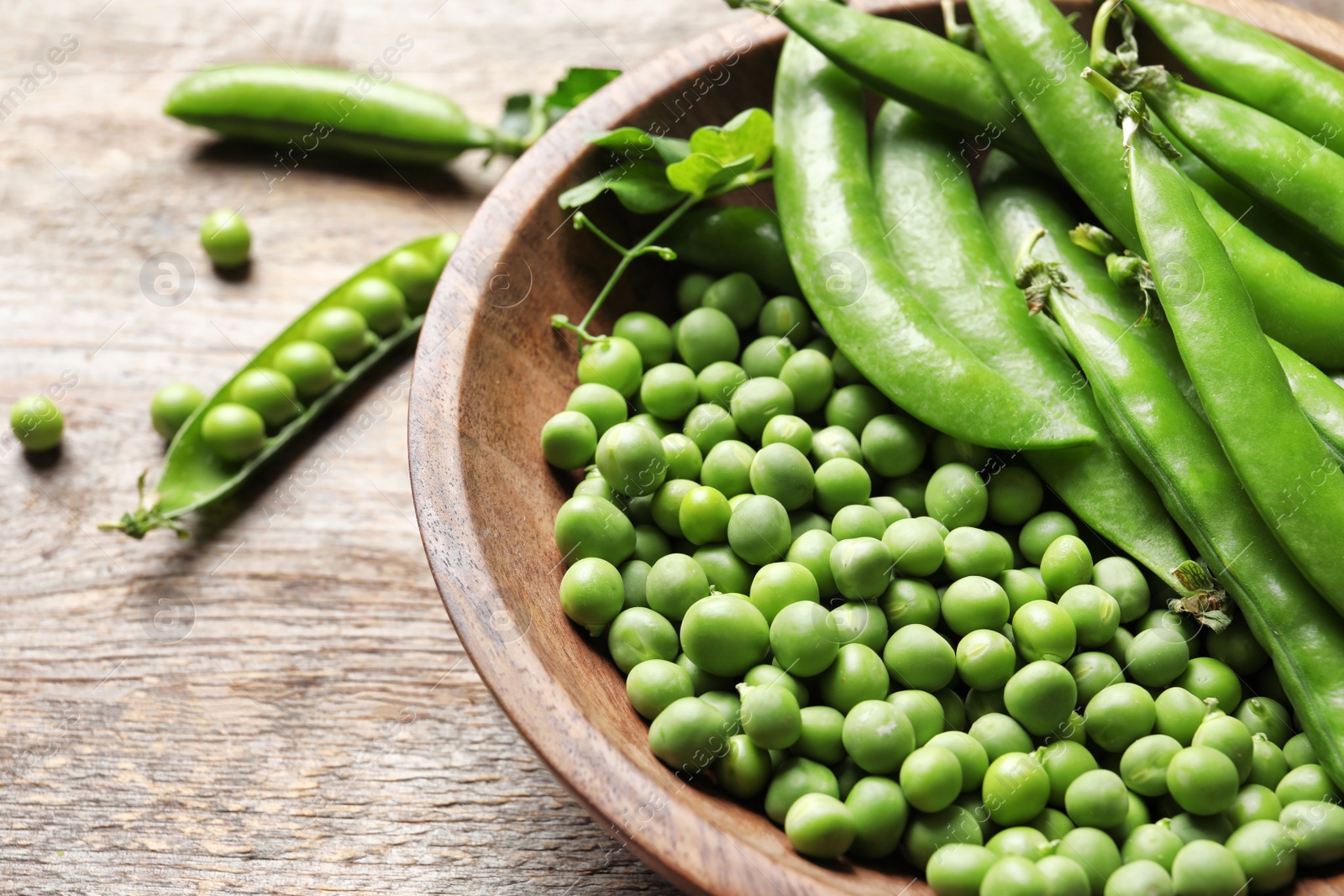 Photo of Bowl with delicious fresh green peas on wooden table