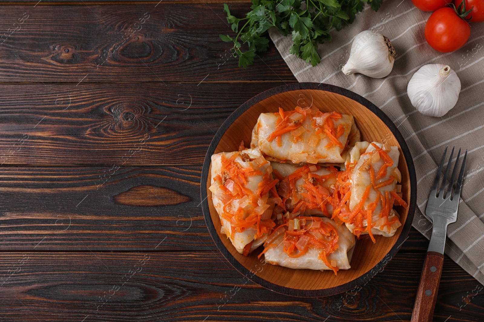 Photo of Delicious cabbage rolls served on dark wooden table, flat lay. Space for text