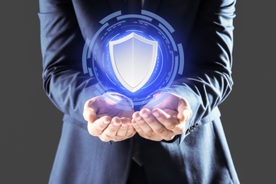 Cyber insurance concept. Man demonstrating shield illustration as symbol of protection, closeup