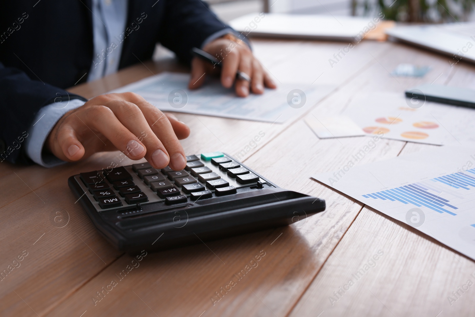 Photo of Tax accountant with calculator working at table in office, closeup