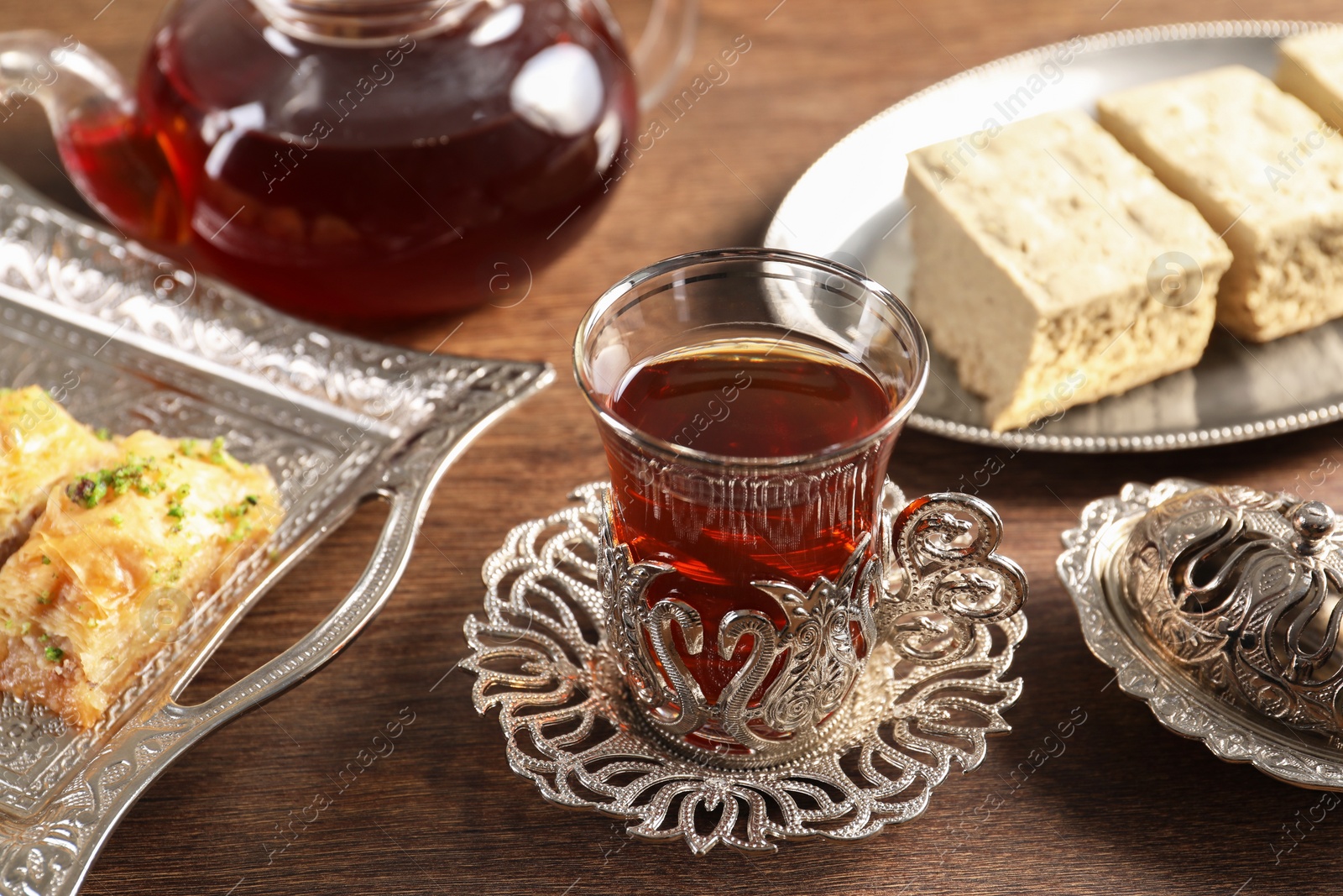 Photo of Traditional Turkish tea and sweets served in vintage tea set on wooden table