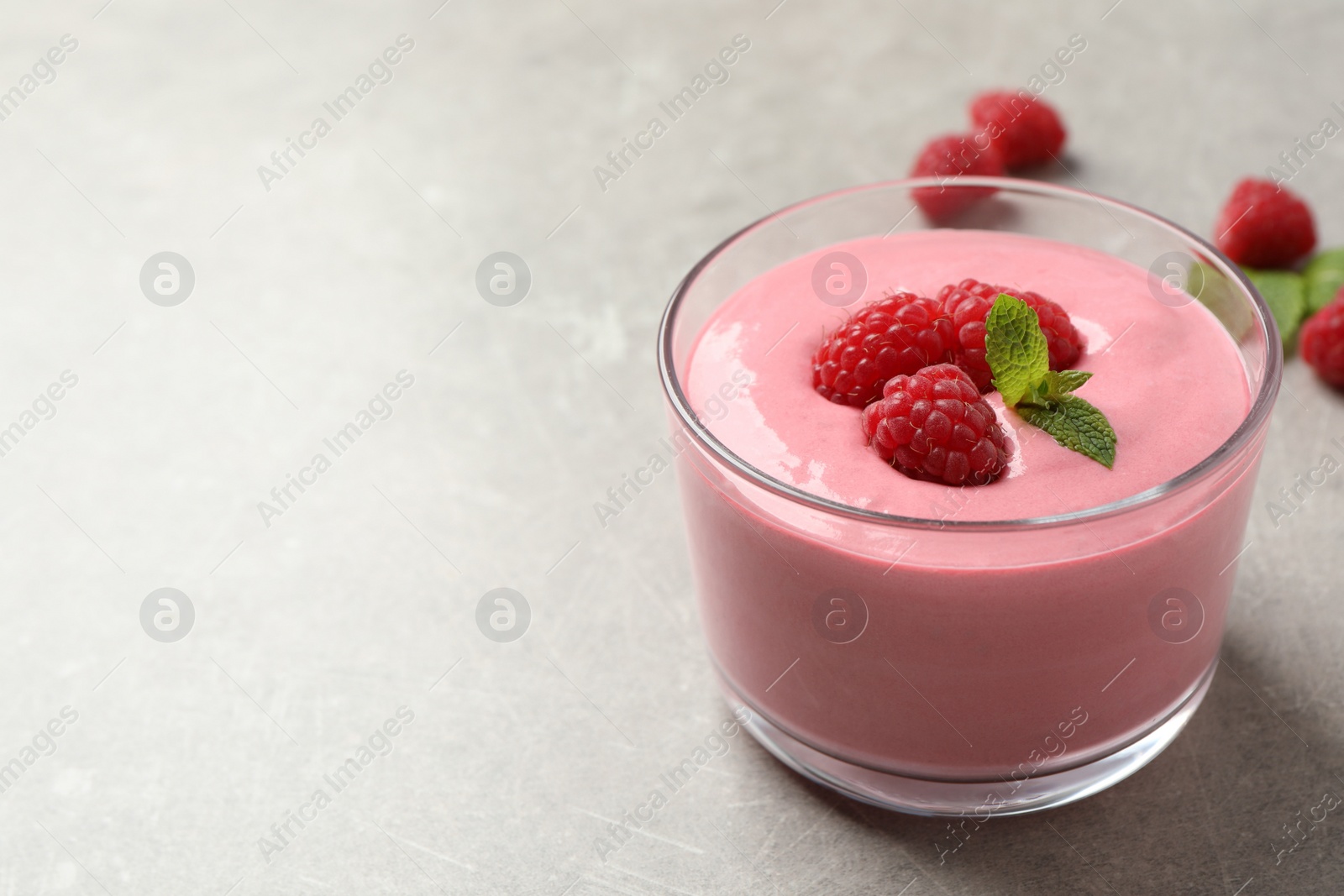 Photo of Delicious raspberry mousse with mint on light grey table, space for text