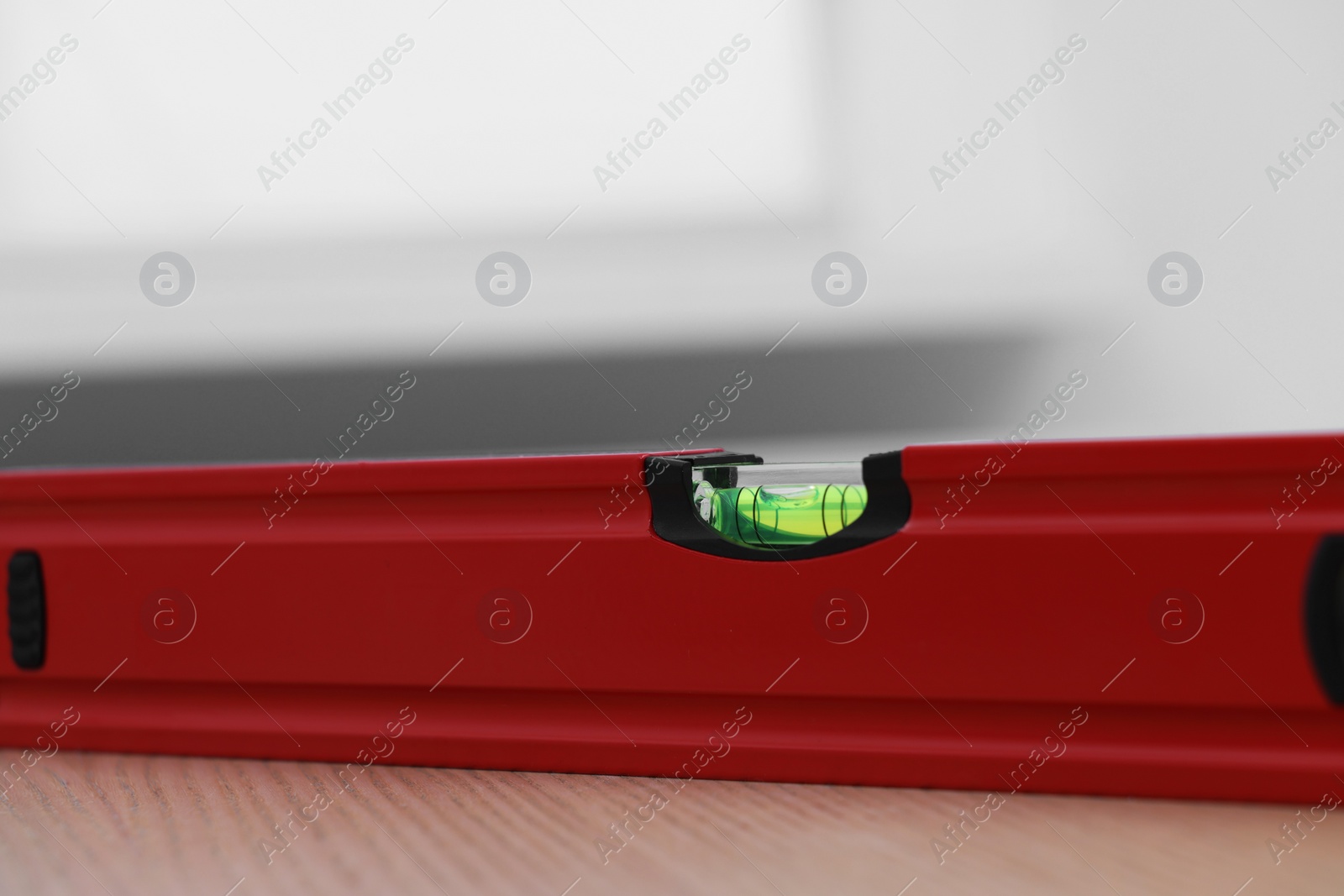 Photo of Red building level on wooden table indoors, closeup