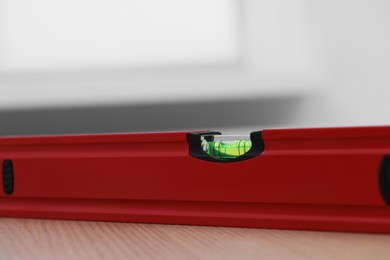 Photo of Red building level on wooden table indoors, closeup