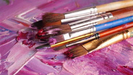 Brushes on canvas with mixed bright paints, closeup