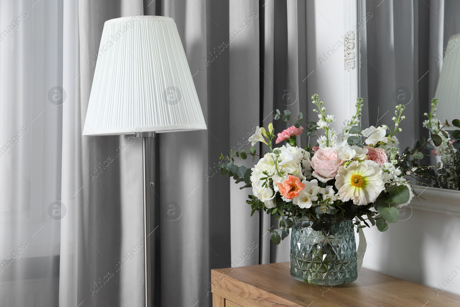 Photo of Bouquet with beautiful flowers on wooden chest of drawers indoors. Space for text