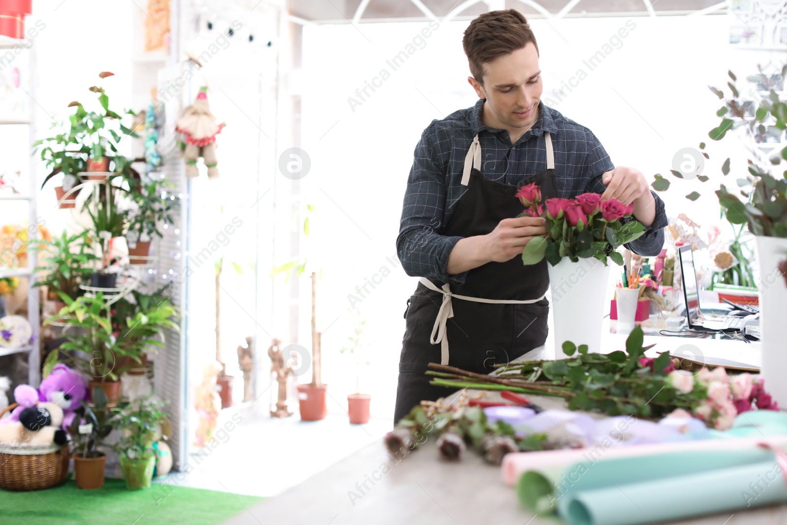Photo of Male florist creating beautiful bouquet in flower shop
