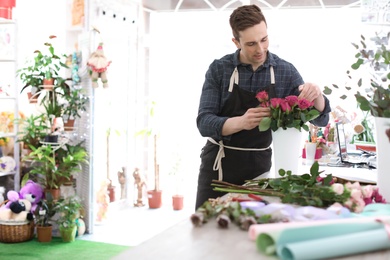 Male florist creating beautiful bouquet in flower shop