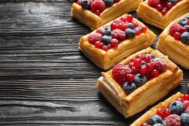 Fresh delicious puff pastry with sweet berries on dark wooden table. Space for text