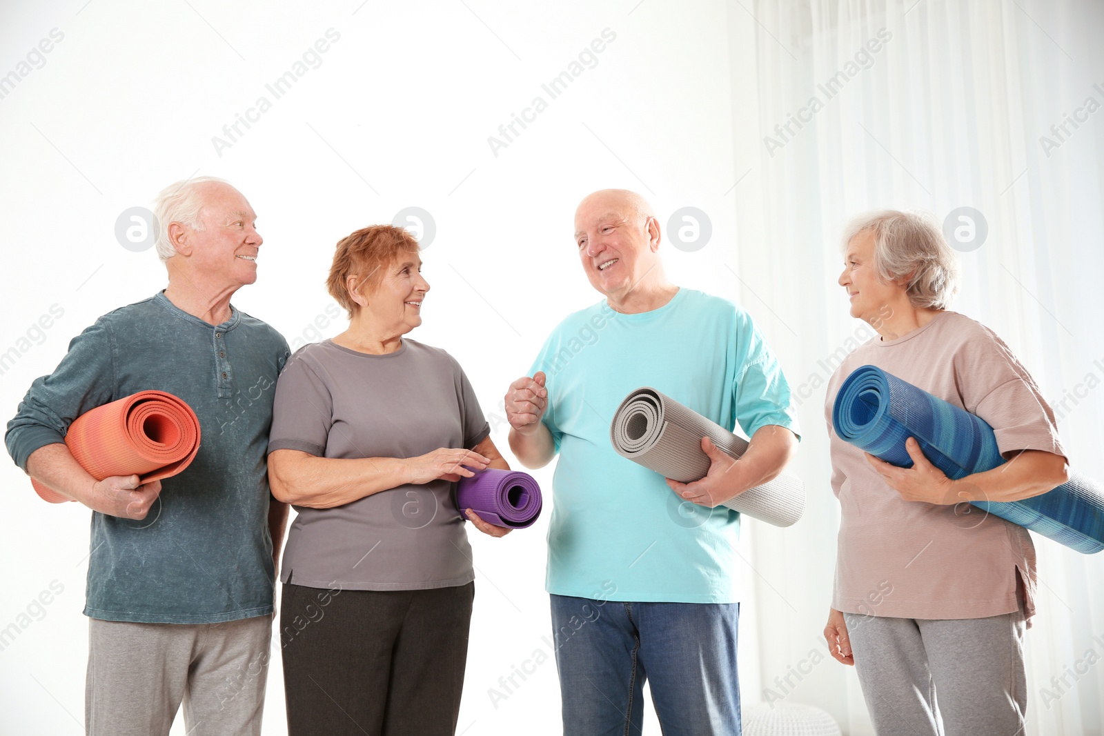 Photo of Elderly people with yoga mats on light background