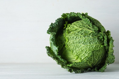 Photo of Fresh ripe savoy cabbage on white wooden table, space for text