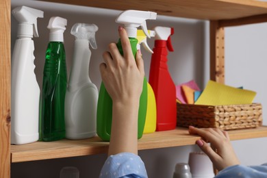 Woman taking detergent from wooden rack in laundry room, closeup