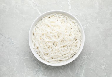 Photo of Bowl with cooked rice noodles on light marble table, top view
