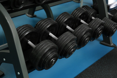 Photo of Dumbbells on rack in gym. Modern sport equipment