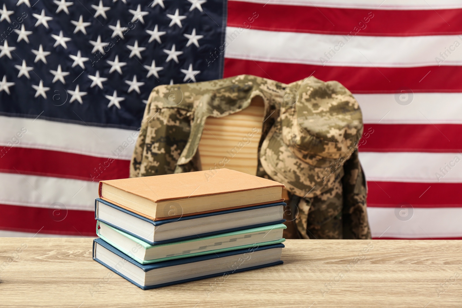 Photo of Books and soldier uniform near flag of United States. Military education