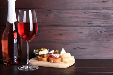 Delicious rose wine and snacks on wooden table. Space for text