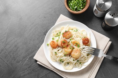 Photo of Delicious scallop pasta with green onion served on grey table, flat lay. Space for text