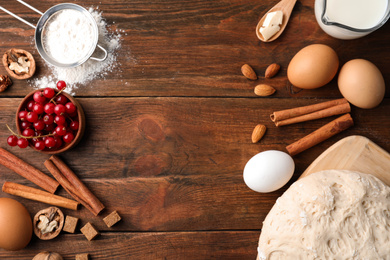 Photo of Flat lay composition with dough on wooden table, space for text. Cooking pastries