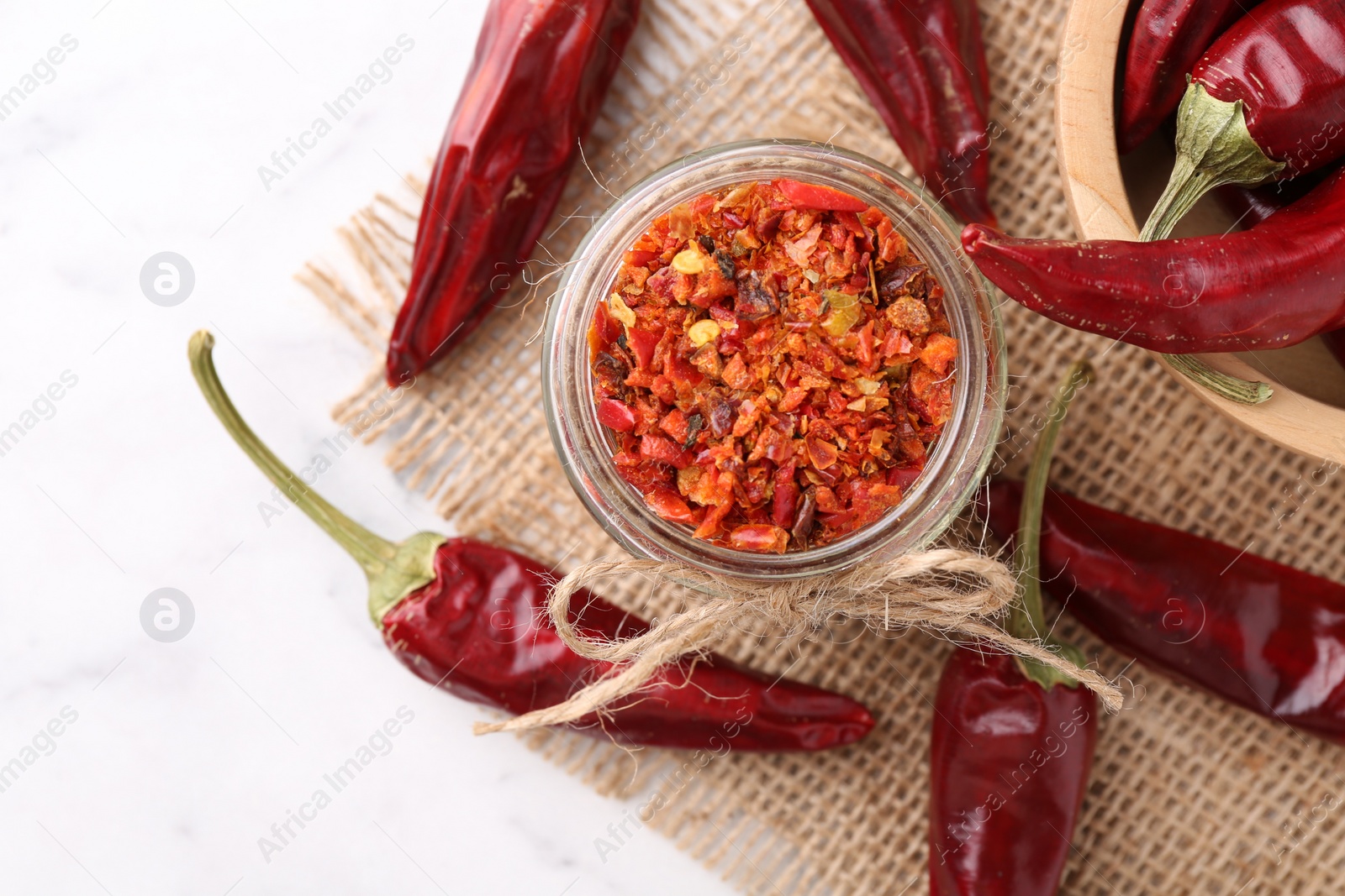 Photo of Chili pepper flakes and pods on white table, top view