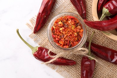 Photo of Chili pepper flakes and pods on white table, top view