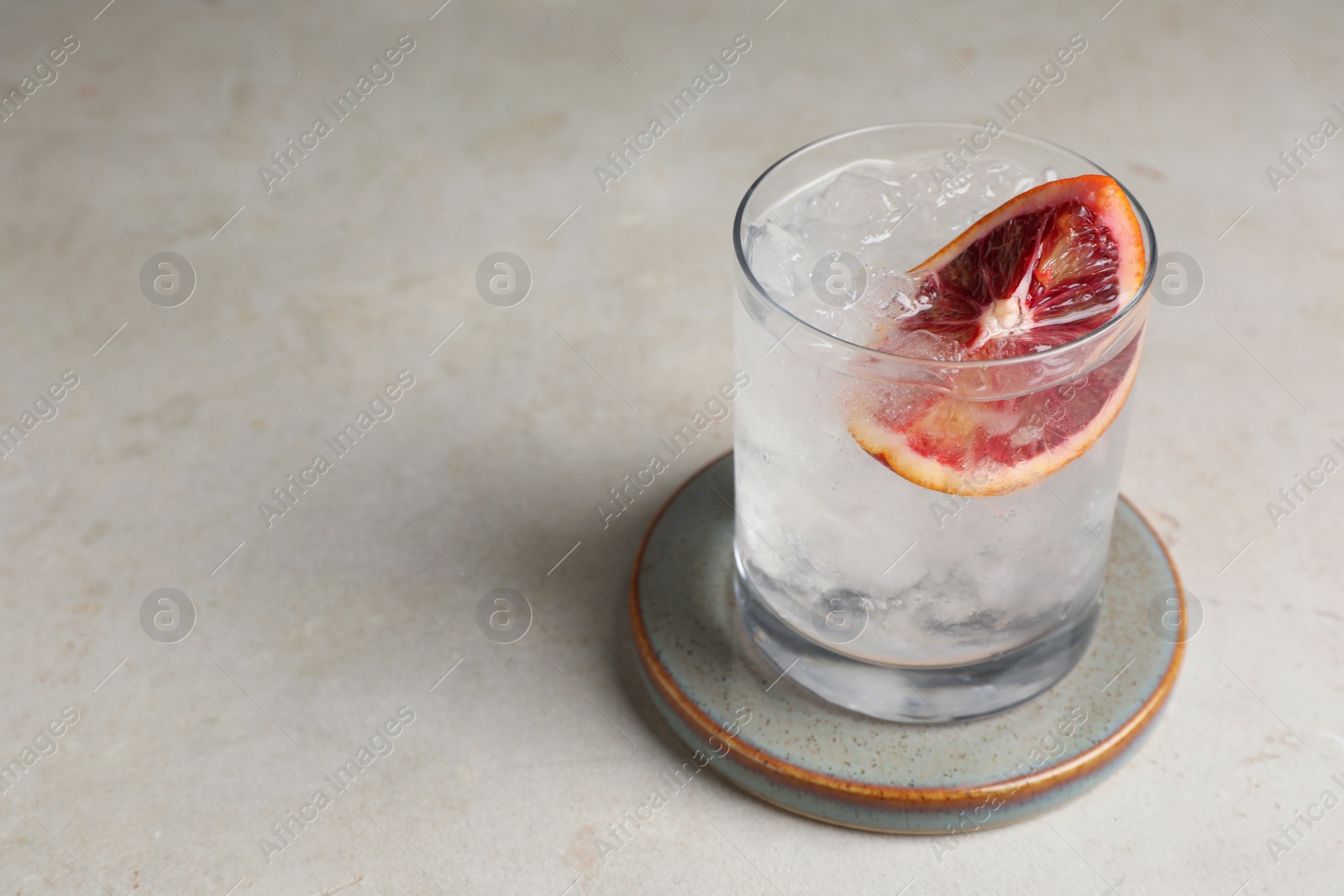 Photo of Delicious refreshing drink with sicilian orange and ice cubes on light table. Space for text