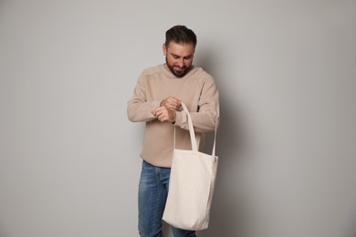 Happy young man with eco bag on light background