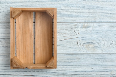 Photo of Empty crate on wooden background, top view with space for text