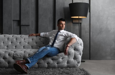 Photo of Handsome businessman on sofa indoors. Luxury lifestyle