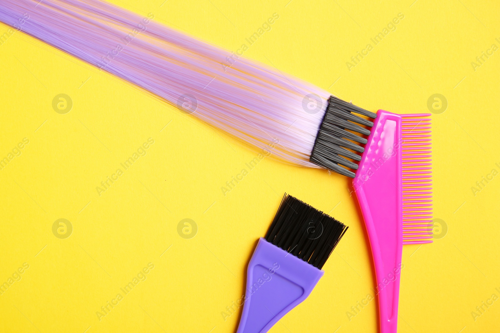 Photo of Flat lay composition with strand of hair and brushes on color background. Space for text