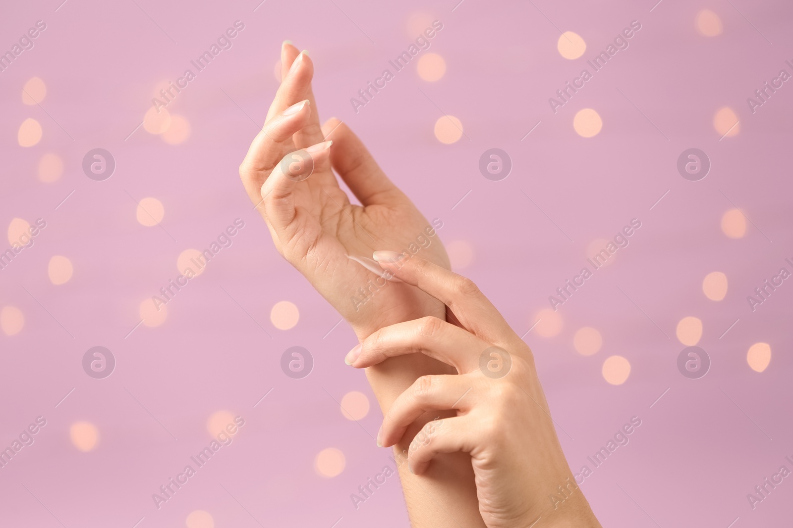 Photo of Woman applying hand cream on blurred background, closeup