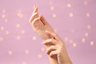 Photo of Woman applying hand cream on blurred background, closeup