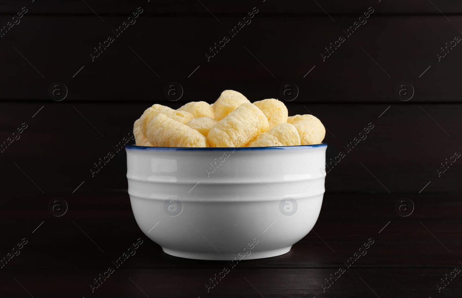 Photo of Bowl of corn sticks on dark wooden table