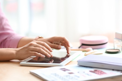 Photo of Female blogger using tablet at table indoors