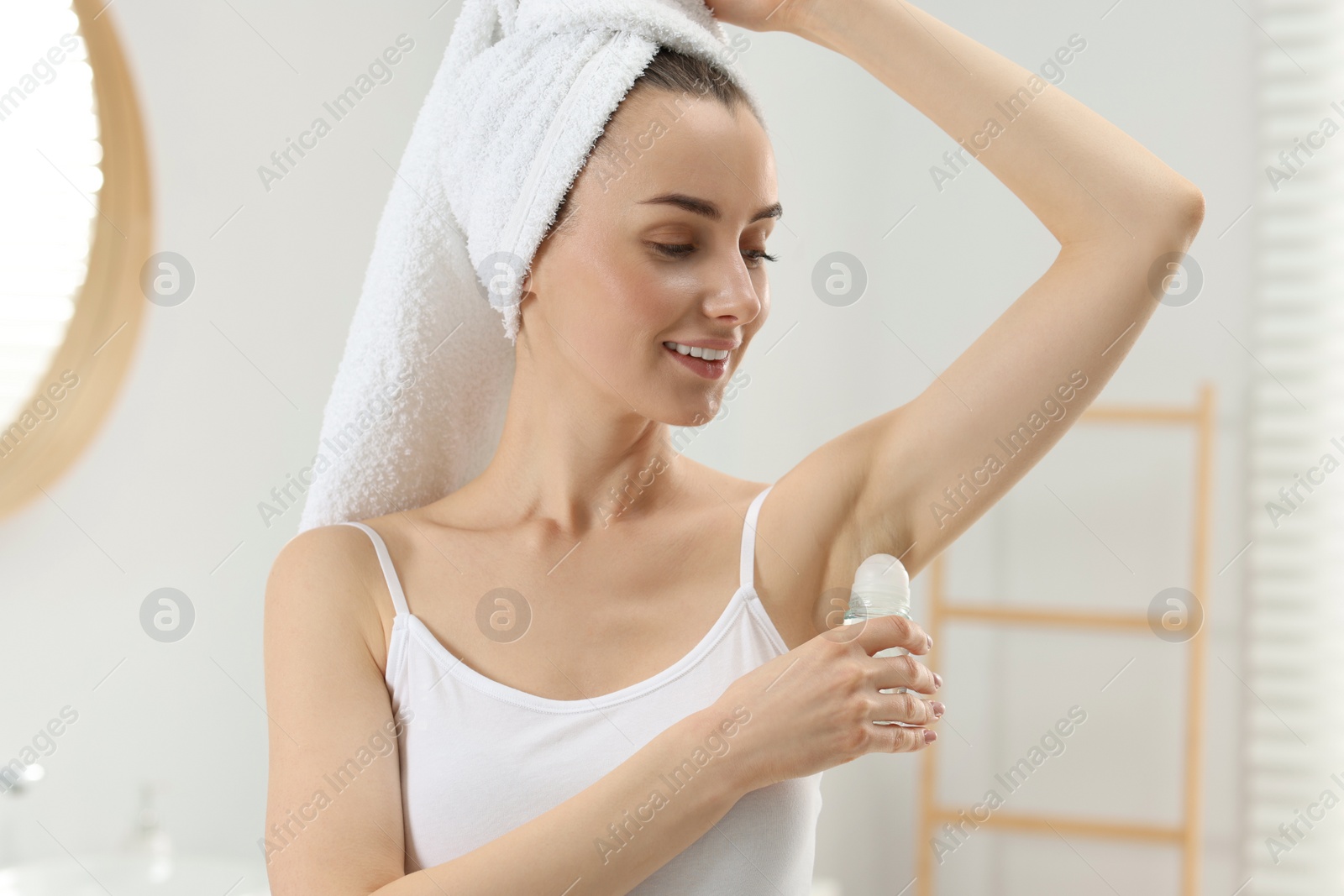 Photo of Beautiful young woman applying deodorant in bathroom