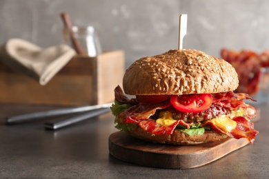 Board with tasty bacon burger on table