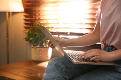 Woman working with modern laptop indoors, closeup