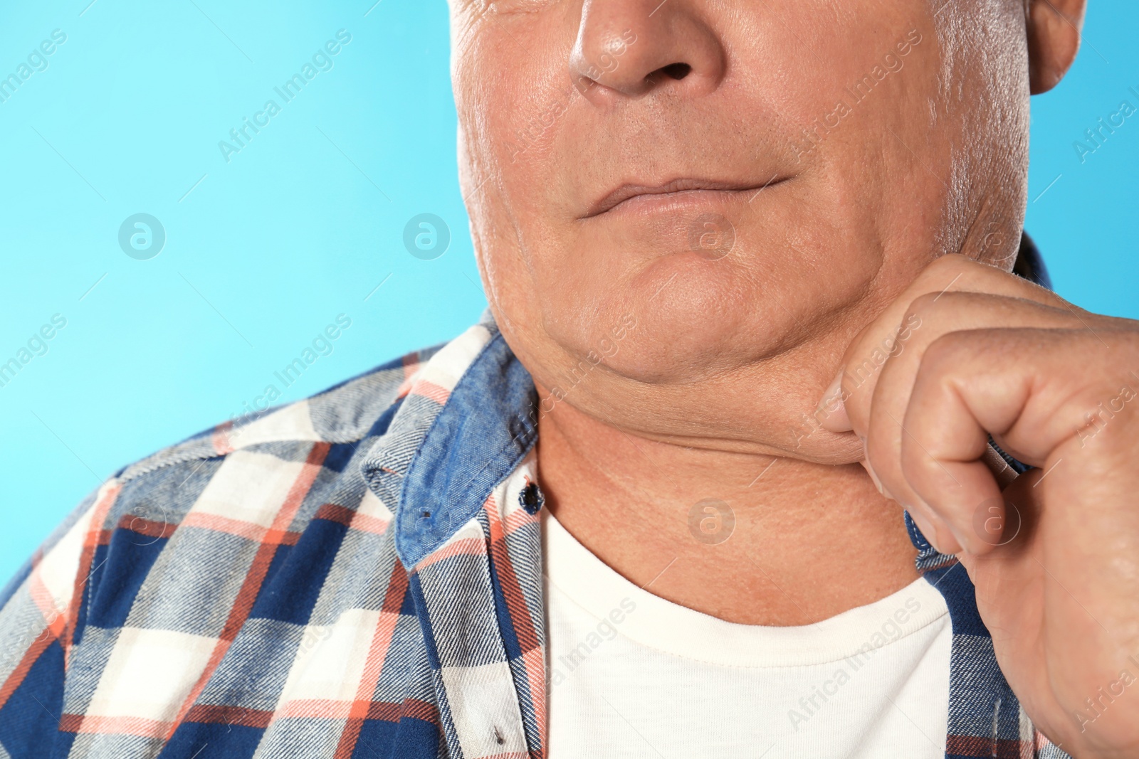 Photo of Mature man with double chin on blue background, closeup